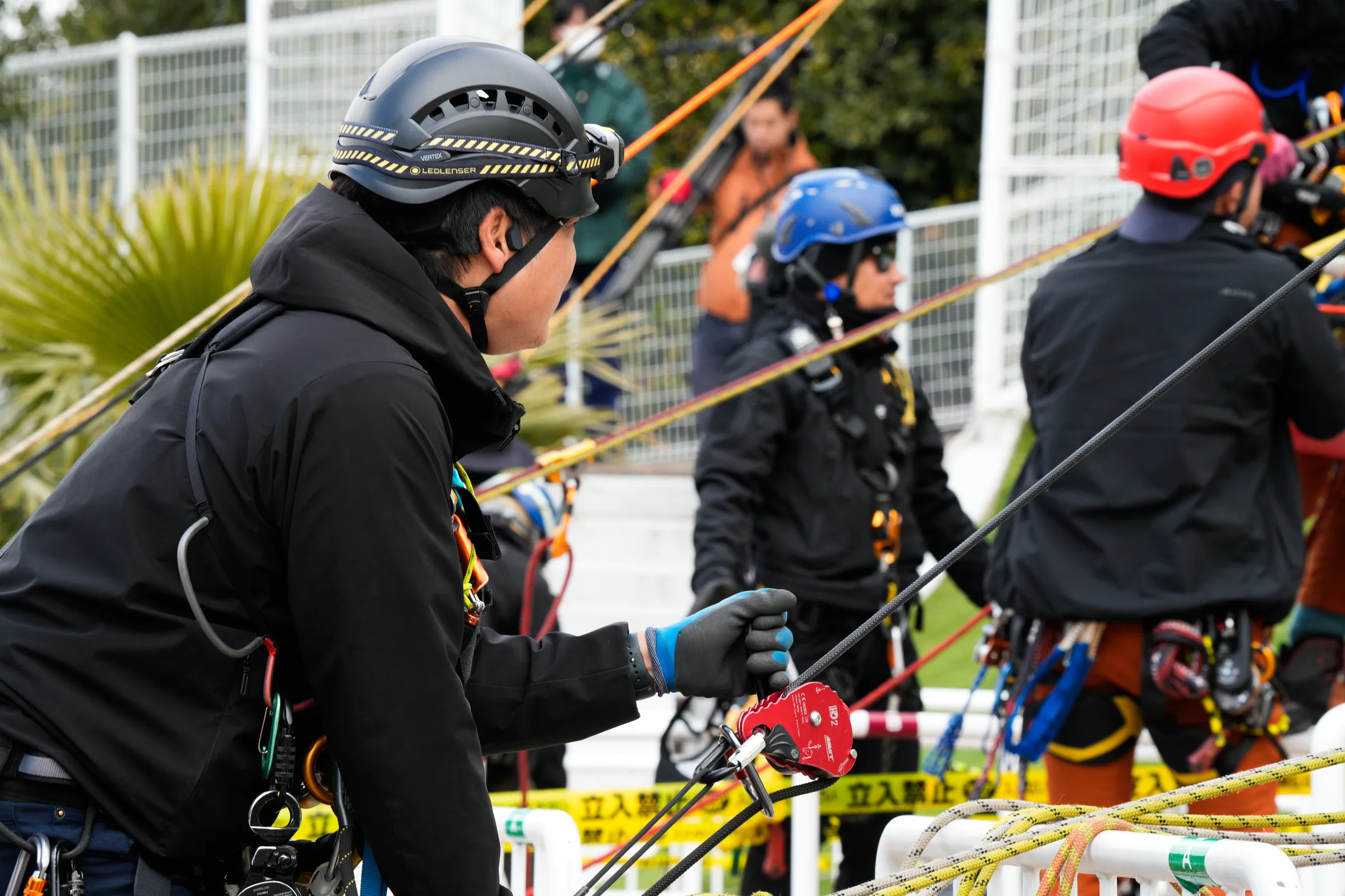 A rope technician working the line beside an RD2 descender, with other teams rigging behind